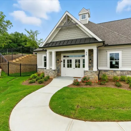Modern suburban house with stone accents, white doors, manicured lawn, curved walkway, and clear blue sky.