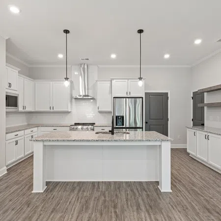 Modern kitchen with white cabinets, gray countertops, stainless steel appliances, and wood-look flooring.