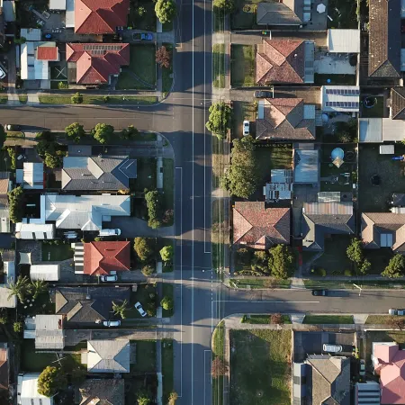 Aerial view of a residential neighborhood with intersecting streets, houses, and green yards on a sunny day.
