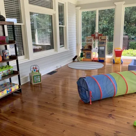a room with a wood floor and a shelf with books and a bookcase with a window