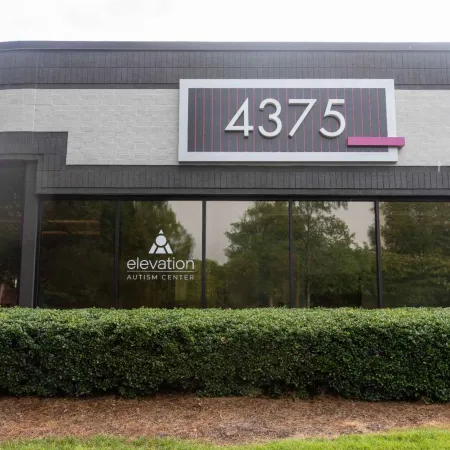 Exterior of Elevation Autism Center building with address number 4375 and greenery in front.