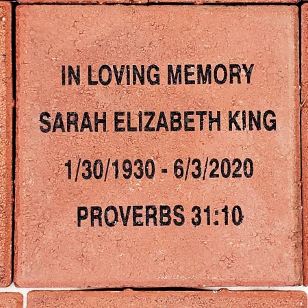 Memorial brick with inscription honoring Sarah Elizabeth King and a Bible verse from Proverbs 31:10.