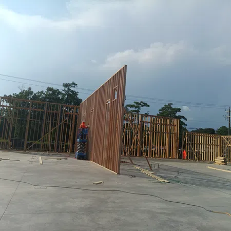 Construction site with wooden framework walls being erected on concrete slab under cloudy sky