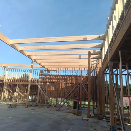 Wooden framework of a building under construction on a sunny day with a clear blue sky.