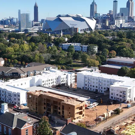 Aerial view of a residential construction site with the Atlanta skyline and Mercedes-Benz Stadium in the background.