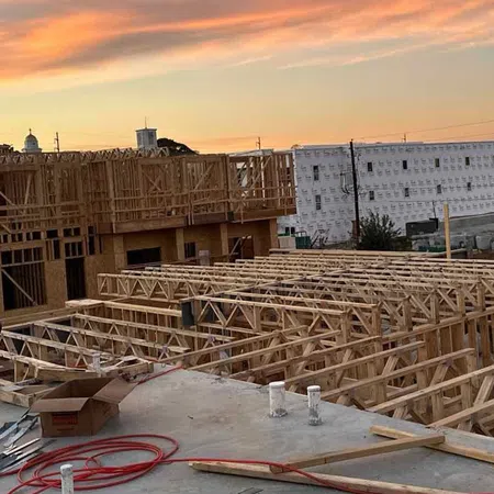 Construction site with wooden framing and workers during sunset showcasing residential building development.