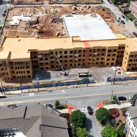 Aerial view of a large building under construction surrounded by roads and other structures in an urban area.