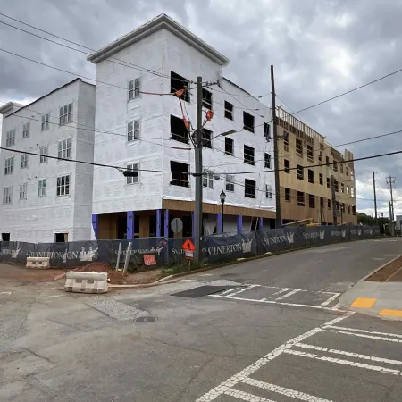 Multi-story building under construction with white sheathing and scaffolding on a cloudy day
