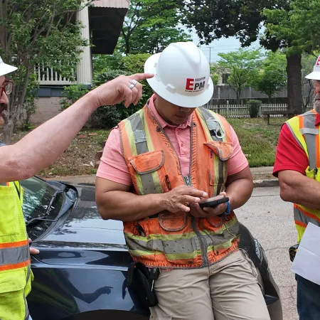 a group of men wearing hardhats and reflectors looking at a phone