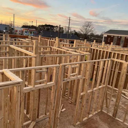 Wooden framework of a building under construction during sunset with some urban buildings in the background
