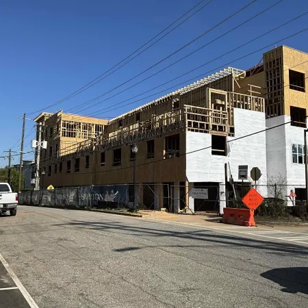 Partially constructed multi-story building with wooden framing and white sheathing under clear blue sky