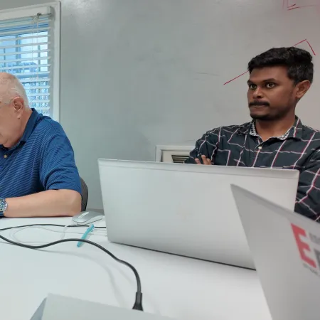 men sitting at a table with laptops