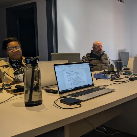 Team of diverse professionals in a modern office meeting room engaged in discussion around a conference table.