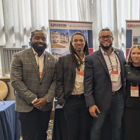 Group of five professionals posing at an Essayon Builders booth at a conference or event.