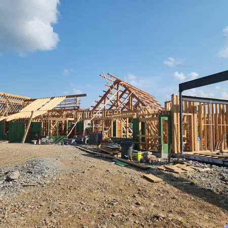 Wooden frame structures of a residential house under construction on a clear sunny day with blue sky.