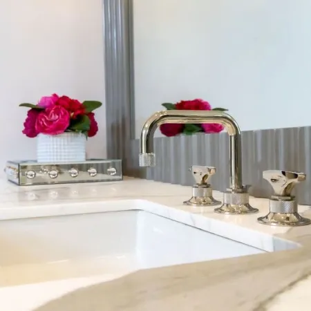 Stylish bathroom sink with modern faucet and decorative flowers in a chic setting.