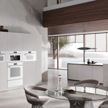 Modern kitchen with sleek cabinetry, elegant dining table, and large windows showcasing a scenic view.