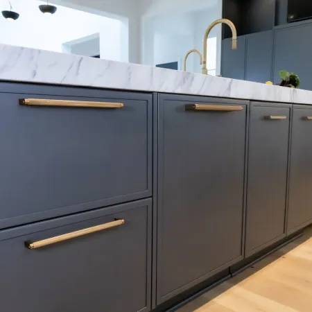 Modern kitchen featuring dark cabinetry and a marble countertop with stylish gold hardware.