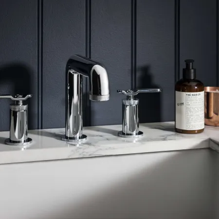 a sink with a bottle of soap and a couple of faucets