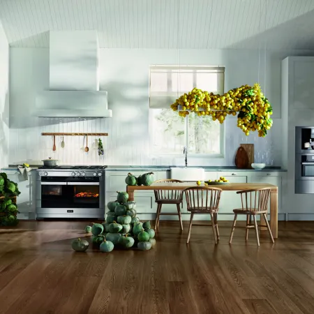 Bright and modern kitchen with lemon decor, wooden furniture, and green vegetables on the floor.