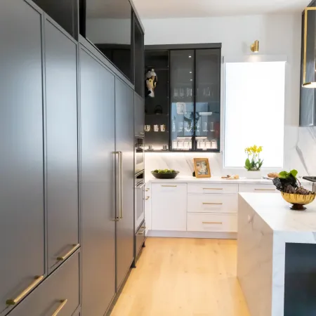 Modern kitchen with sleek gray cabinets, white marble countertops, and natural light highlighting fresh fruit.