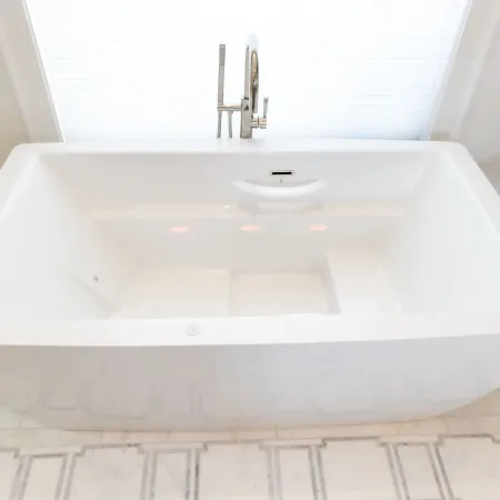A spacious, modern white bathtub with sleek design, situated in a bright bathroom.