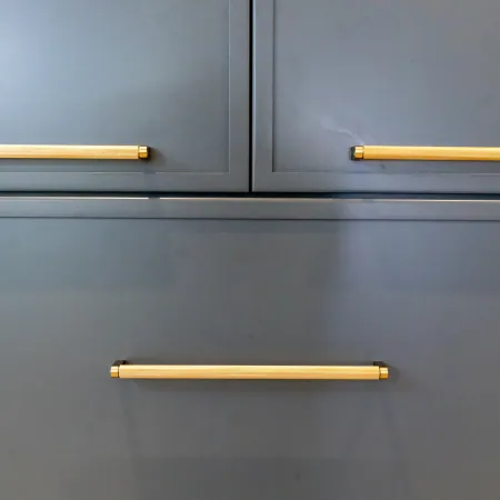Close-up of modern gray cabinet drawers with brass handles.