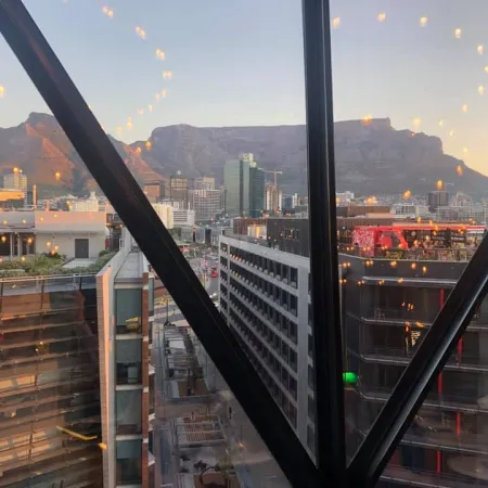 City skyline view from high-rise window with mountain range and sunset light reflections