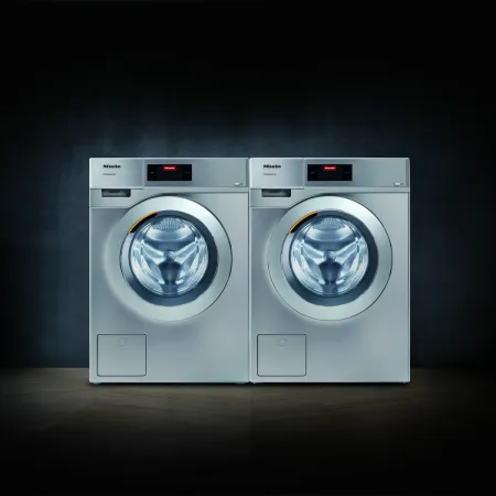 Two modern Miele washing machines displayed against a dark background for a sleek look.