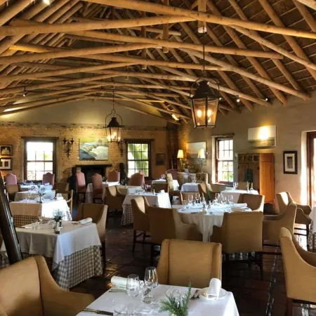 Cozy rustic restaurant interior with wooden beams, elegant tables, and soft lighting creating a warm atmosphere.