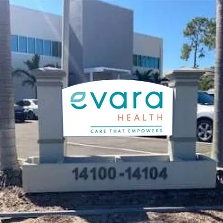 Evara Health sign with address 14100-14104 outside a modern office building with parked cars and palm trees.