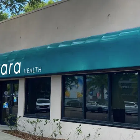 Exterior of Evara Health clinic with teal awning and large front windows on sunny day