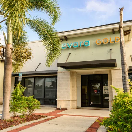 Exterior view of Evara Gold store with palm trees and shrubs under blue sky