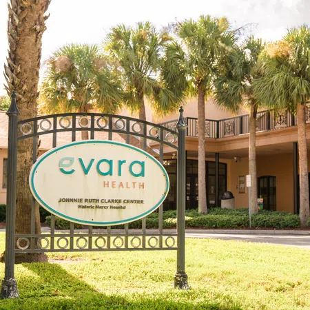 Evara Health Johnnie Ruth Clarke Center sign in front of building with palm trees and clear sky