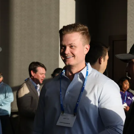 Group of professionals talking and networking at a business event in natural sunlight indoors.