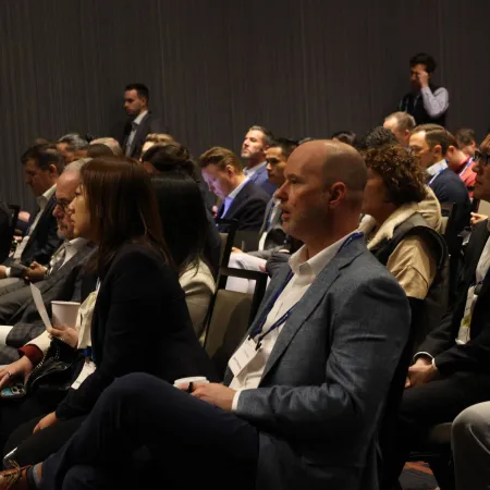 Business professionals attentively listening at a conference or seminar in a dimly lit room.