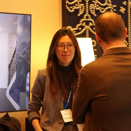 Three professionals engaged in discussion at an indoor event with a display in the background