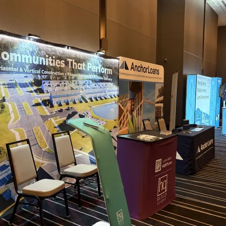 Trade show booths featuring Communities That Perform and AnchorLoans with promotional displays and seating.
