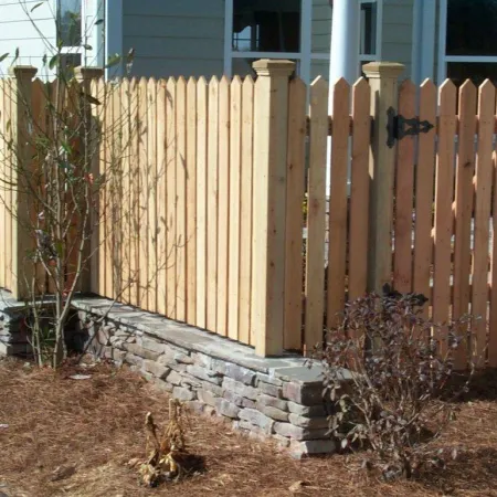 a fenced in yard with a tree and a house in the background