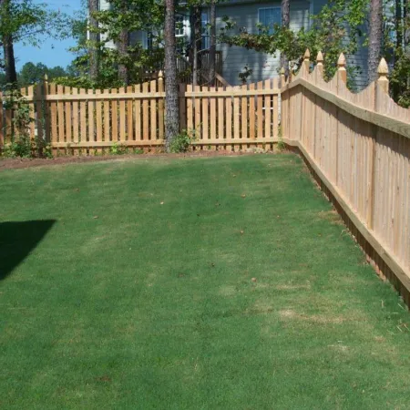 a fenced yard with a wooden gate and a building in the background