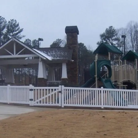 a white picket fence in front of a house with a slide