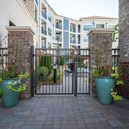 a gate with plants and a building in the background