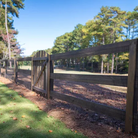 a fenced in area with a metal gate and trees in the background