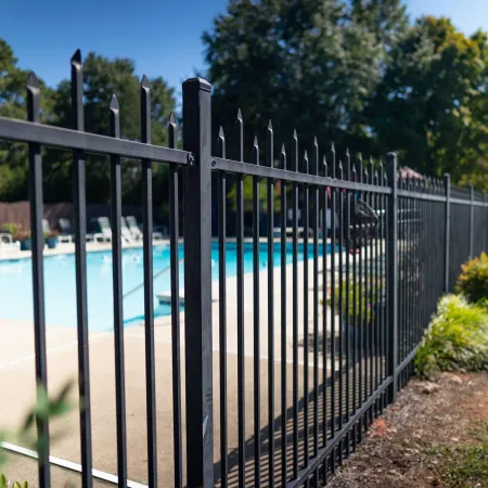 a black gate with a pool in the background