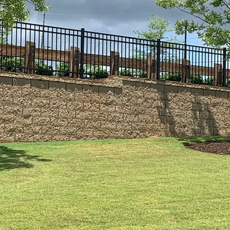 a fenced in area with a stone wall and grass