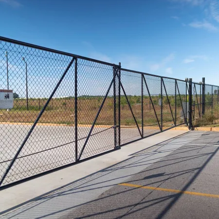 a fenced off area with a road and trees in the background