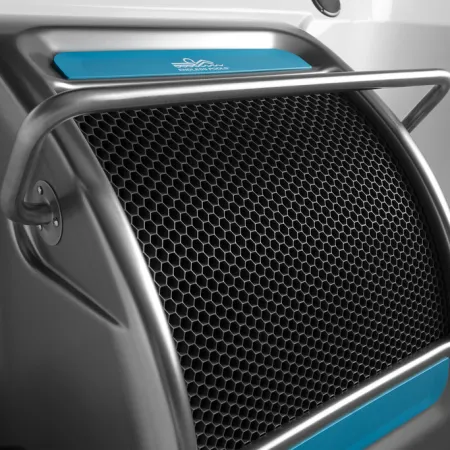 Close-up of a black honeycomb grille on a sleek metallic surface with a blue label and metal guard rail.