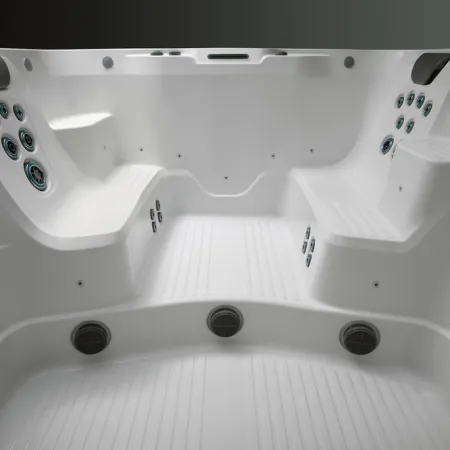 Empty white modern hot tub with built-in seats and multiple water jets in a clean indoor setting
