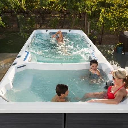 Family enjoying a swim spa with swim and relaxing areas in a sunny backyard patio setting