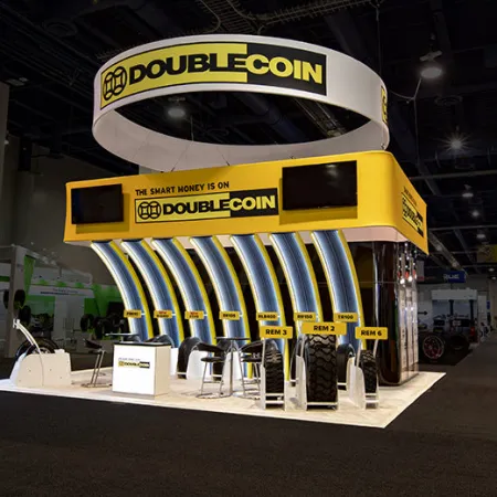 Double Coin trade show booth with yellow and black branding showcasing tires and displays in an exhibition hall.